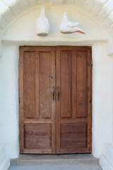 A wooden front door on the white concrete wall.