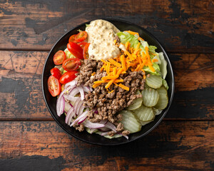 Cheeseburger, hamburger or burger keto salad with beef, fresh tomatoes, red onion, pickled gherkins, lettuce and home made sauce dressing
