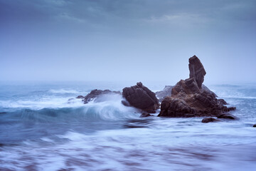 Waves against the lonely rocks in the Mediterranean Sea on a cloudy morning, Costa Brava, Girona, Spain.