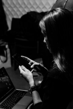 woman smartphone reads news laptop dark room