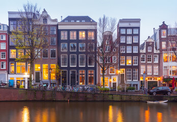 Beautiful old houses on the city waterfront of Amsterdam at sunset.