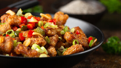 Stir fry salt and pepper pork loin with herbs in black bowl. Asian food