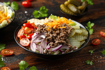Cheeseburger, hamburger or burger keto salad with beef, fresh tomatoes, red onion, pickled gherkins, lettuce and home made sauce dressing