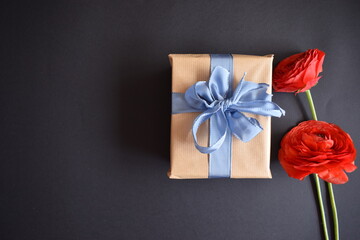A beautiful gift and two red roses on a black background