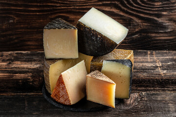 Various kind of cheese. head of handcrafted hard cheese on a dark background. banner, menu, recipe place for text,