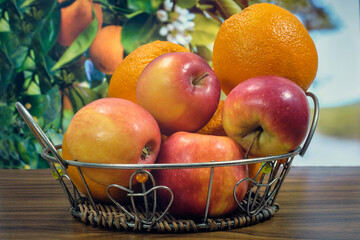 Oranges and apples on the table in a basket