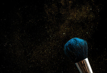 make-up brush with powder of different colors on a dark background like space dust