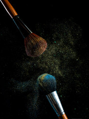 make-up brush with powder of different colors on a dark background like space dust