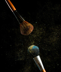make-up brush with powder of different colors on a dark background like space dust