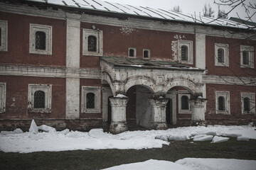 A beautiful old building. Red brick facade. Old beautiful architecture. Winter day. Cloudy weather. Snowy winter day.