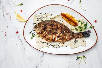 Delicious Grilled dorado fish with lemon and parsley. Whole Bbq sea bream baked. Dorado grill. Ketogenic, keto or paleo diet lunch, Healthy food trend. Top view