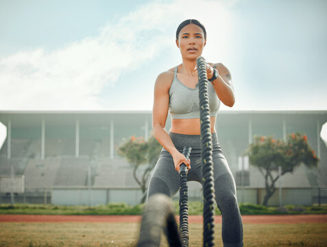 Shes Always Ready For Battle. Cropped Shot Of An Attractive Young Female Athlete Exercising With Battle Ropes Outside.