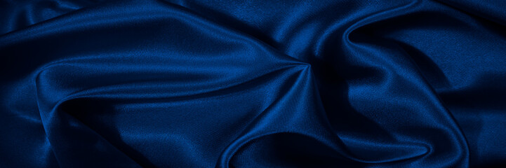 Navy blue silk satin. Smooth silky shiny fabric. Dark luxury background for design. Christmas, New Year, festive, party. Web banner. Wide. Long. Panoramic.