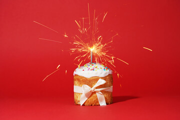 Easter cake with baw and sparkler on red background, easter food. minimal concept