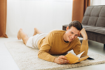 Obraz premium Handsome young man in yellow casual clothes sitting at home reading a book