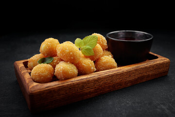 Cheese nuggets balls with sweet sauce on a wooden board