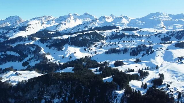 Ski area Stoos in the Swiss Alps, air survey mountain peaks, and rocks covered with snow and blue sky in winter. Stoos, Schwyz, Switzerland.