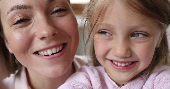 Close up happy beautiful loving mother her cute preschool 5s daughter staring at camera, make funny faces, fooling around, grimacing looking overjoyed, record video for social media. Fun, love concept