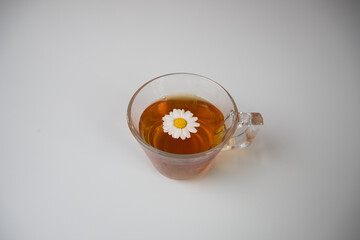 chamomile tea with a chamomile flower inside on white background.