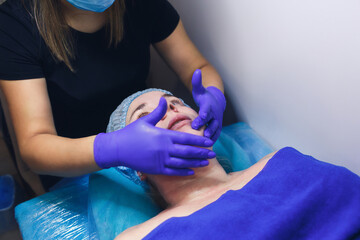 facial massage for rejuvenation to a woman lying on a stretcher in a spa center