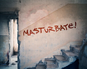 The text Masturbate!, written on the wall of an old ruined abandoned house with red spray.
