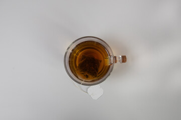 glass of tea with a tea bag in it on white background.
