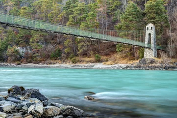 Fotobehang Under the suspension bridge of Stams flows the emerald River Inn. On the shore is one of the two natural stone pylons through which, the suspension ropes of the bridge are led. © BIB-Bilder