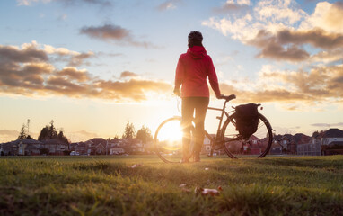 Adventurous Woman Standing with a bicycle at a Park in Modery City Suburbs.