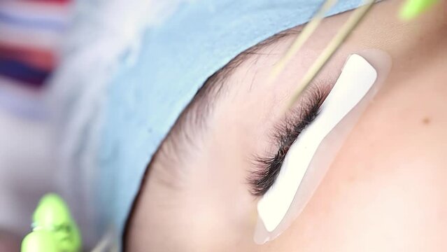 macro shot of the eyelash extension procedure, the master glues the eyelash with tweezers