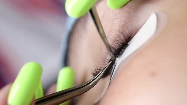 macro shot of the eyelash extension procedure, the master glues the eyelash with tweezers