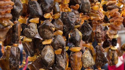 Hanging green and orange amber beads close up. 
Slavic culture. Amber jewelry.  Wallpaper. Texture.