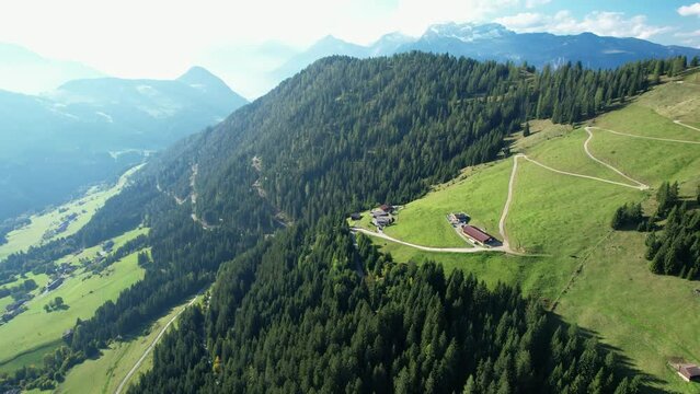 Drone shot of a beautiful farmhouse surrounded by alpine mountain landscape and green alp meadows. Hiking vacation in Tyrol, Austria.