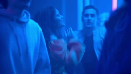 A crowd of people dancing on the dance floor of a nightclub under the light of colored spotlights. Night club