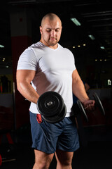Fototapeta na wymiar Male bodybuilder engaged with dumbbells in the gym