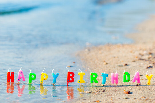 Happy birthday colorful candles on a beach