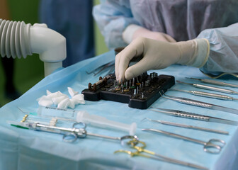Surgical instruments in the operating room. Tooth implant surgery. The implant surgeon selects...