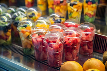 fruit slicing in a cup. Exhibition of a plastic box with fresh cut pieces of fruit in the store. Convenience, healthy