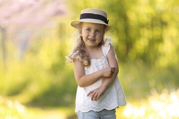 Summer portrait of a little beautiful curly-haired girl in a straw hat on a summer meadow. Healthy girl without allergies. High quality photo