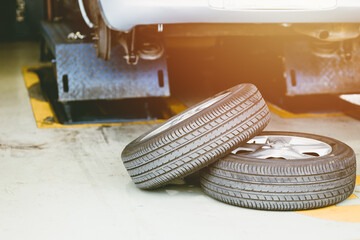 Car in under service lifted for tire replace in auto garage, checking vehicle brake and suspension for safety travel.