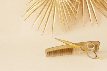 Hairdressing scissors and comb in gold color on a yellow background. Hair salon accessories and decorative leaves - obrazy, fototapety, plakaty