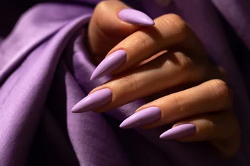 Foto auf Acrylglas Maniküre Mädchenhand mit eleganter Maniküre in violetter Farbe auf violettem Seidenhintergrund