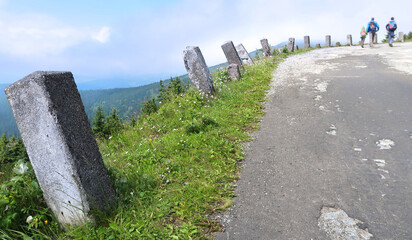 Stone bollards on tourist path to Vrbatova Bouda in Krkonose (Giant Mountains), Czech Republic, Bohemian Region. Blurred walking tourists visible in the distance.