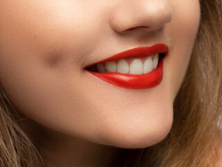 Fototapeta premium Close-up shot of sexy woman's lips with red lipstick and clean skin. Beautiful spa portrait with a snow-white smile. Spa and cosmetics, dentistry and cosmetology