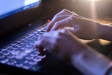 Girl is working on a laptop at night, hands closeup.