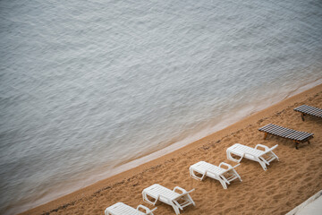 Chaise lounges (loungers) on a deserted beach by the lake after rain. High quality photo