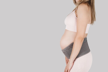 Pregnant woman belly in prenatal pregnancy maternity belt. Orthopedic abdominal support waist, back, abdomen band. Belly brace or band for pregnancy. Horizontal web banner. Torso of pregnant model.