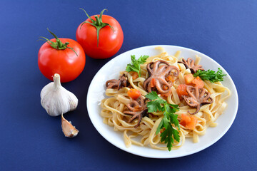 italian pasta with octopus, tomatoes, garlic and parsley, close-up