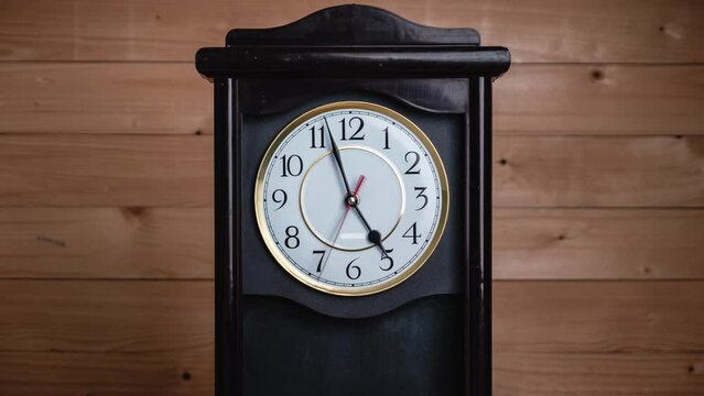 Timelapse of vintage clock with full turn of time hands at 5 am or pm on wooden background. Old Retro wall clock with white circular dial. Old-fashioned antique clock. Arrows second, minute, and hour