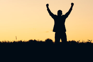silhouette of a man raising his arms up, meeting a new day. overcoming difficulties