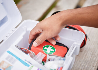 Everything he needs to treat your injuries. High angle shot of an unrecognizable male paramedic looking in his first aid kit while standing outside. - obrazy, fototapety, plakaty